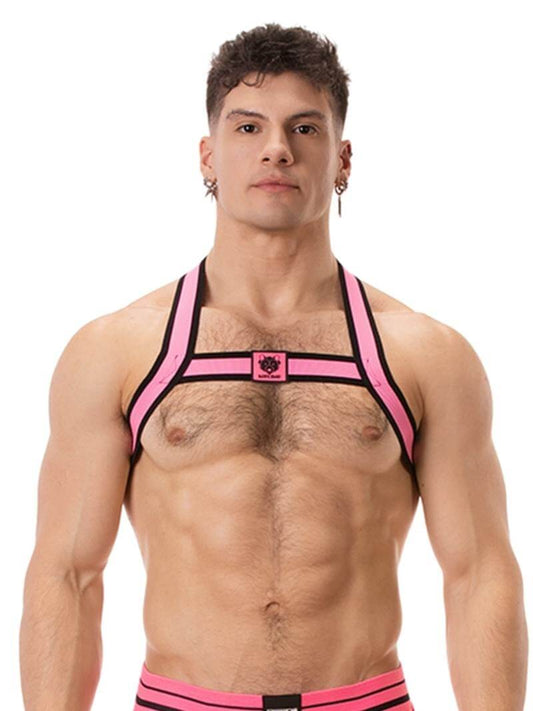 A model wearing a neon pink and black elastic chest harness with the BARCODE Berlin brand emblem on the front horizontal strap.