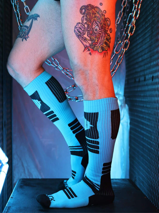 Person wearing knee-high socks with black stripes, standing against a dark background.