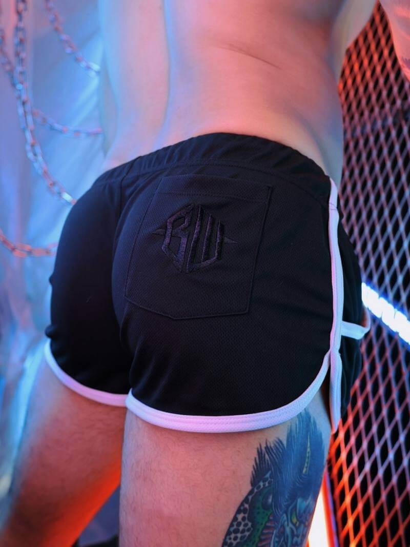 Person wearing black athletic shorts with a logo on a blurred background