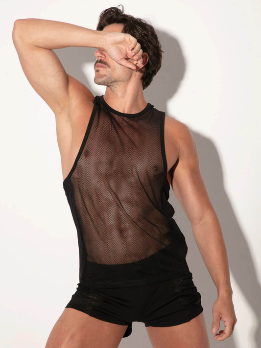 Man wearing a sheer black tank top and black shorts against a white background