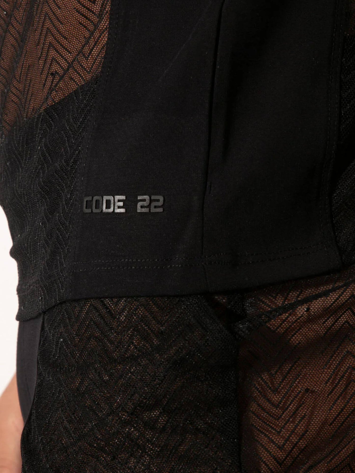 Close-up of a black garment with 'CODE 22' branding on a white background