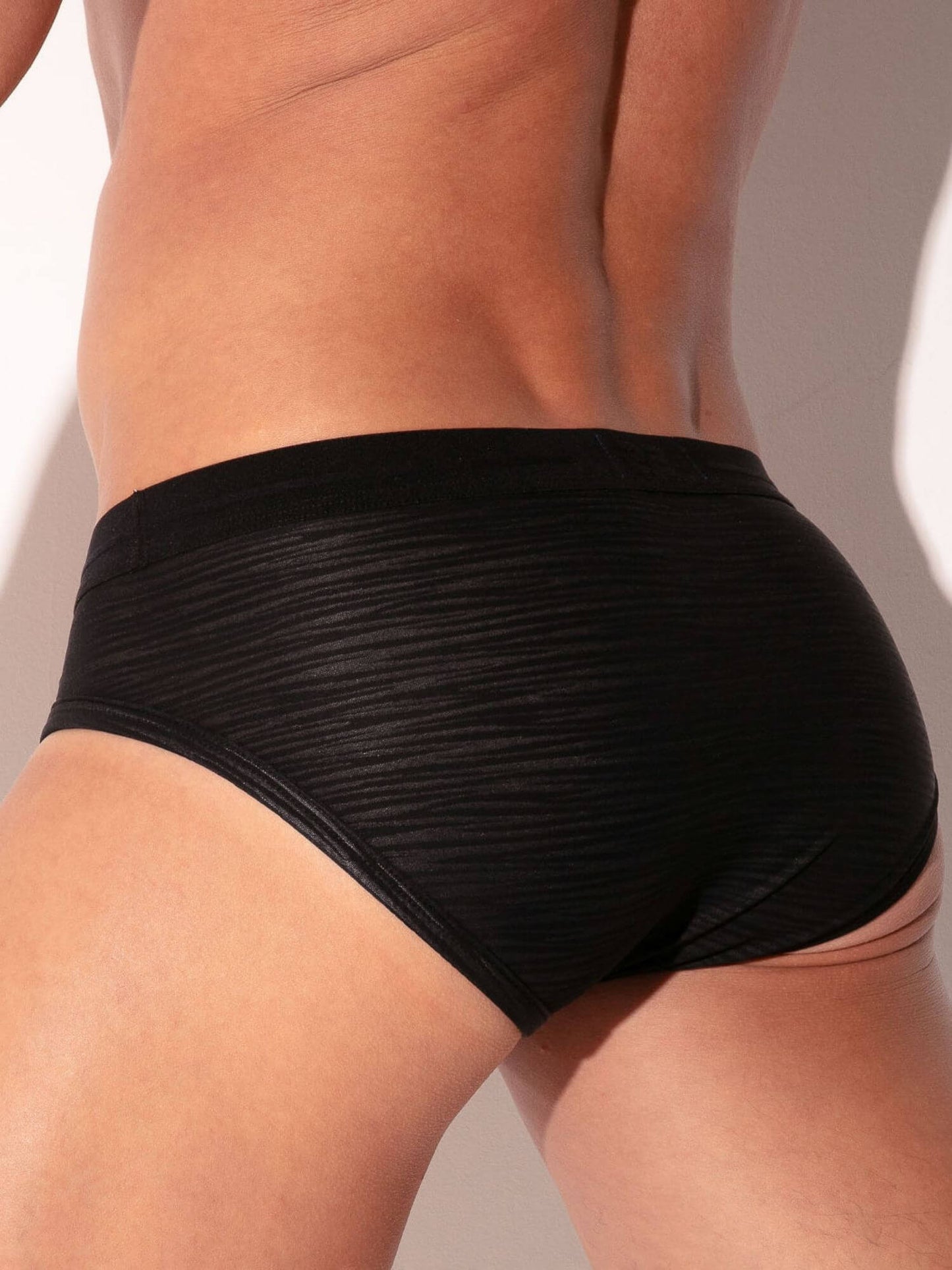 Black underwear worn by a person on a plain background