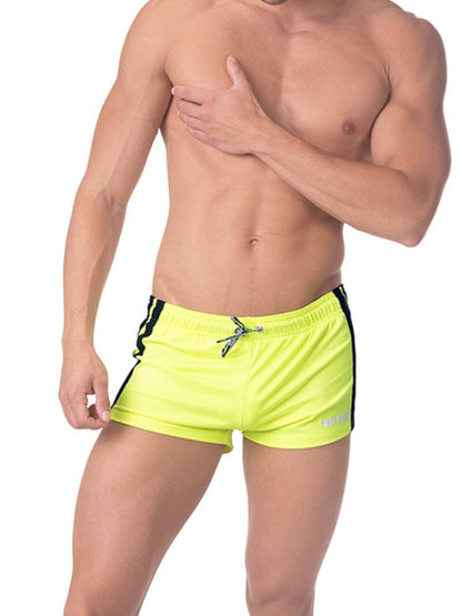 A model wearing royal blue short-legged shorts with sporty side stripes and a drawstring waist.
