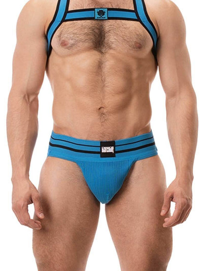 A model wearing a blue BARCODE Berlin Andreus jockstrap, with the brand label visible on the striped waistband, showcasing the product's design and fit.