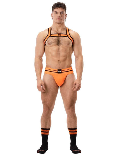 A male model wearing a neon orange and black elastic chest harness with the BARCODE Berlin brand emblem on the front horizontal strap.