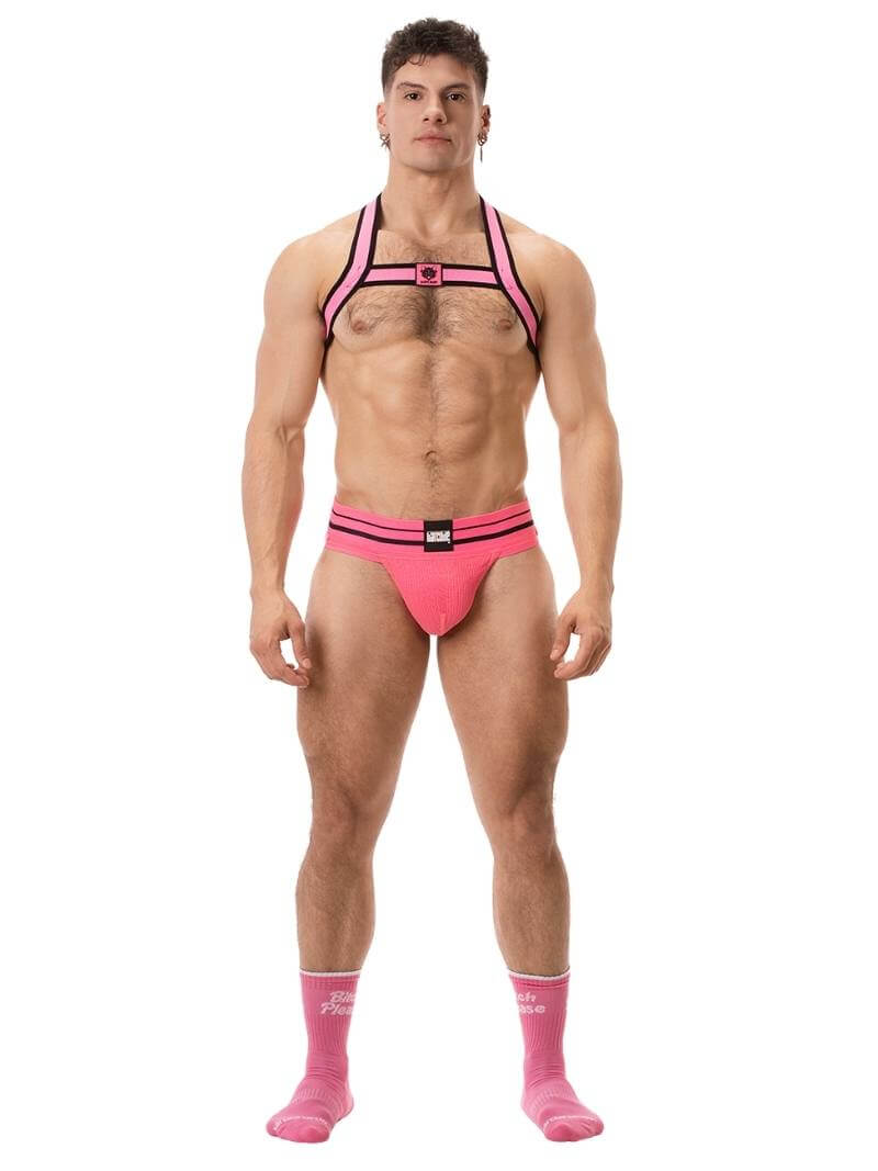 A model wearing a pink BARCODE Berlin Andreus jockstrap, with the brand label visible on the striped waistband, showcasing the product's design and fit.