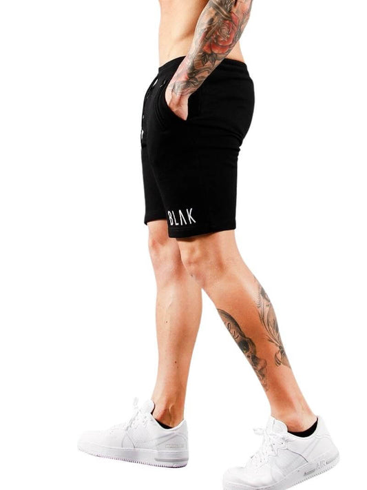 Person wearing black shorts with 'BLAK' branding on a white background