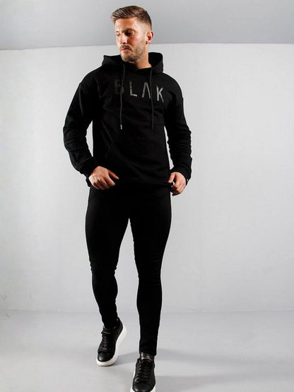 Man wearing a black hoodie with 'BLAK' branding on a gray background