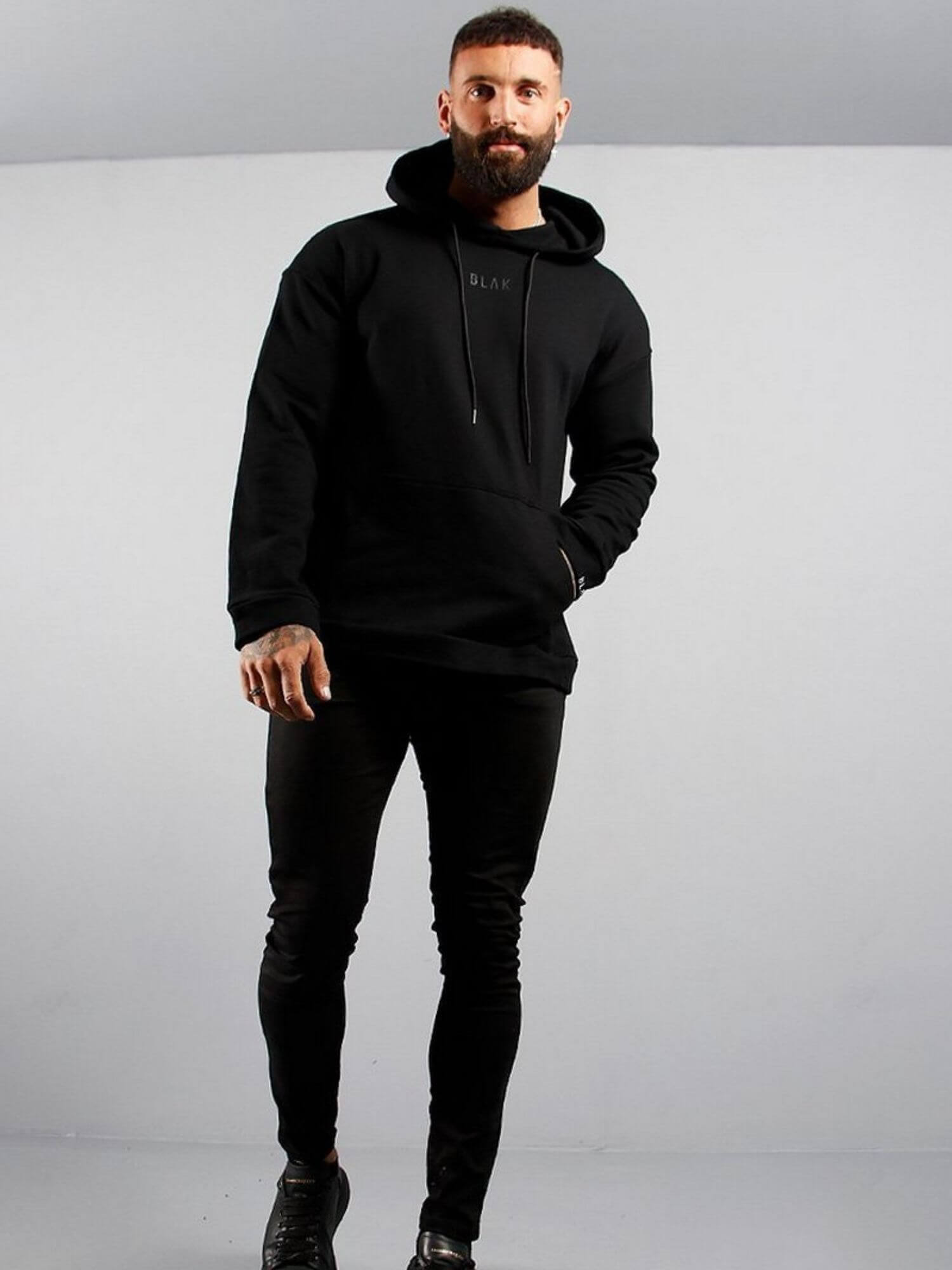 Man wearing a black hoodie and pants on a gray background