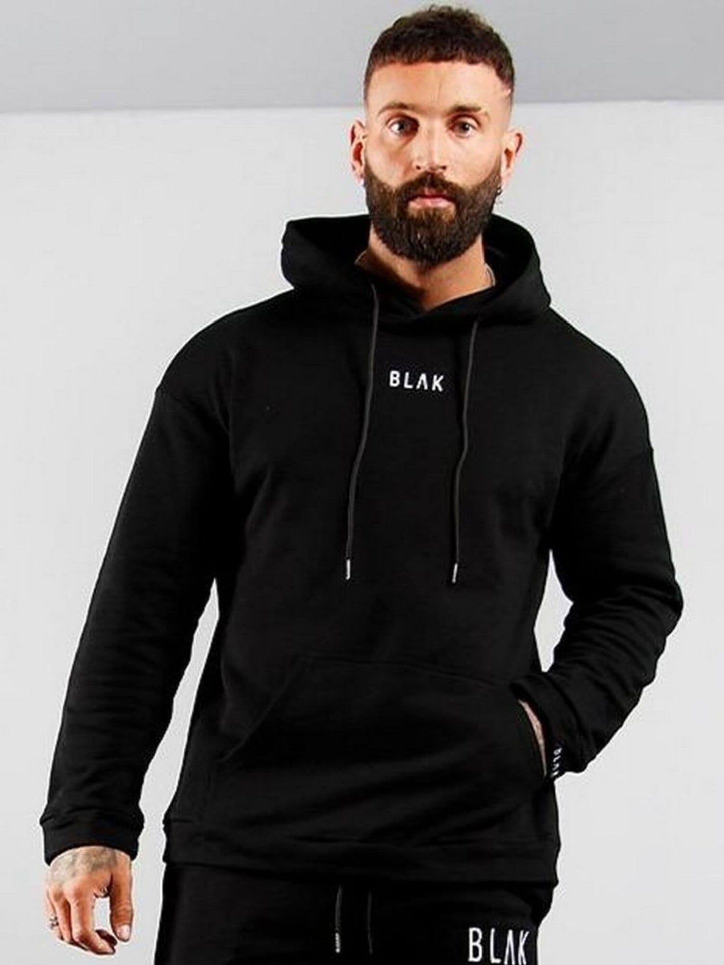 Man wearing a black hoodie with 'BLAK' branding against a gray background