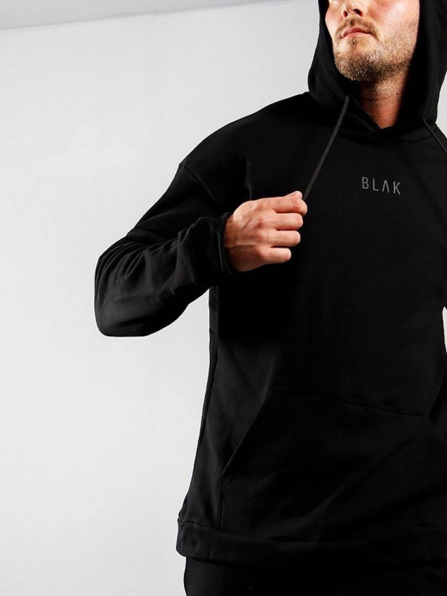 Person wearing a black hoodie with 'BLAK' branding on a white background