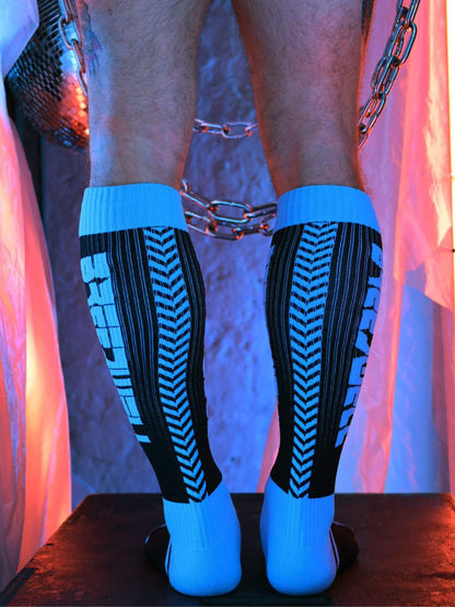 Person wearing black and aqua patterned knee-high socks with a chain accessory.