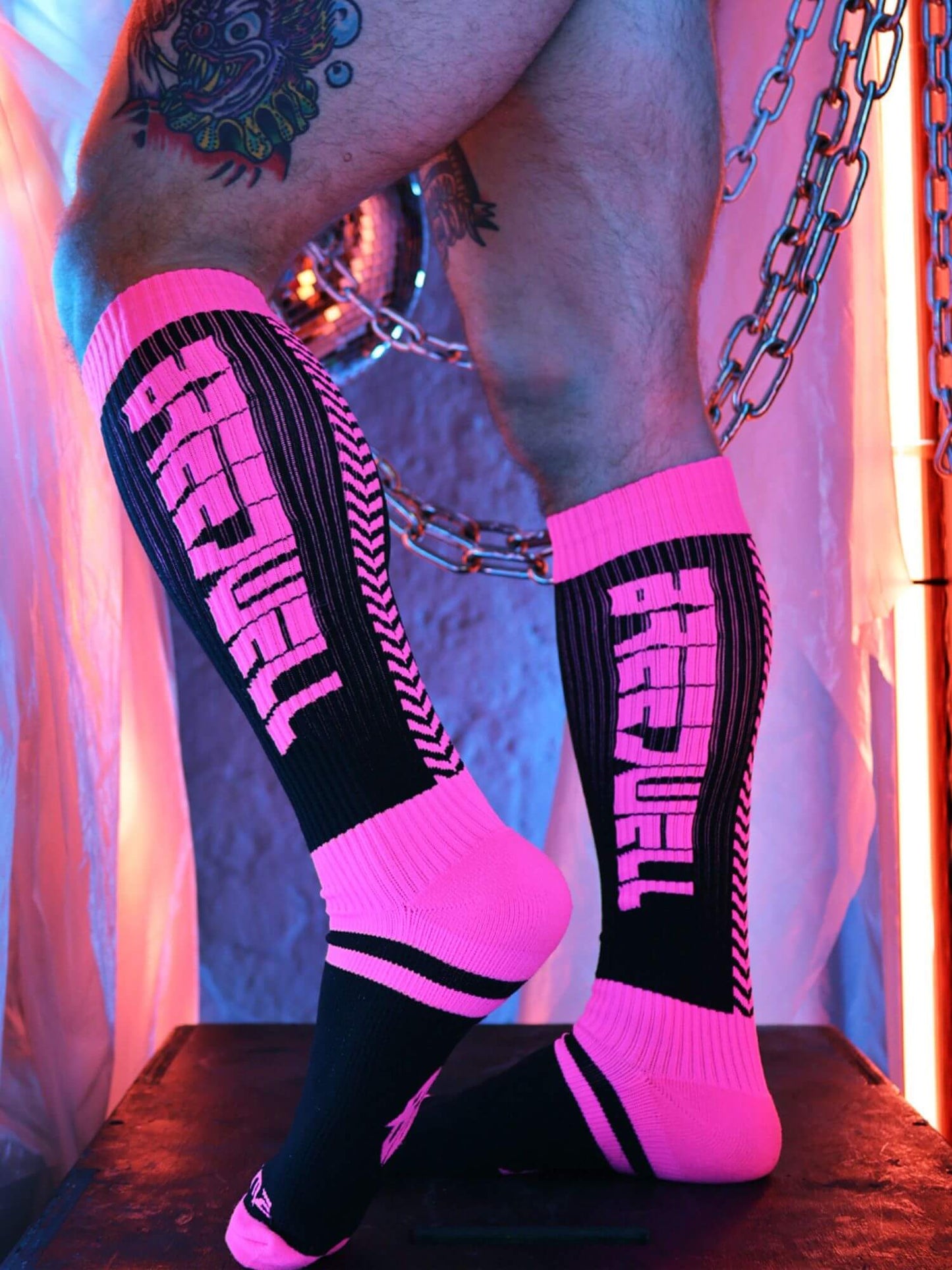 Person wearing pink and black socks with a neon-lit background.