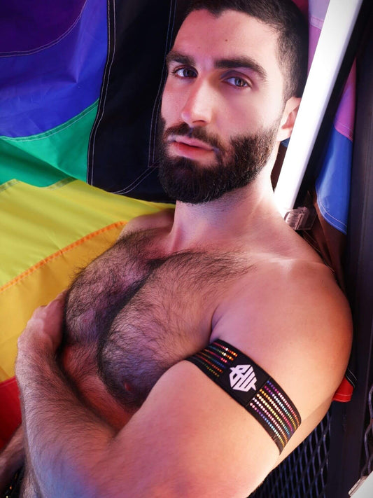 Man with a beard and tattoo holding a rainbow flag