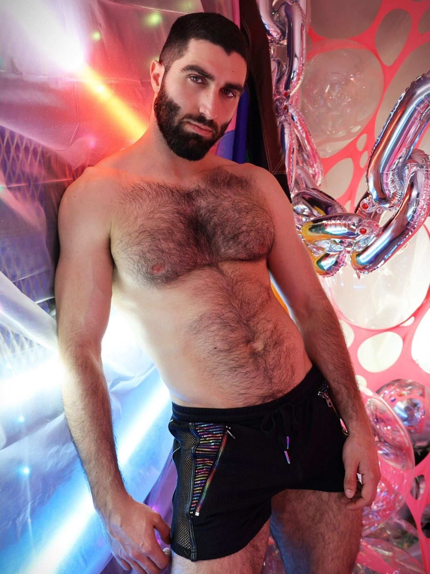 Man wearing black underwear with colorful patterns against a vibrant, abstract background