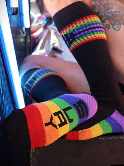 Person wearing rainbow-patterned socks with a visible brand logo.