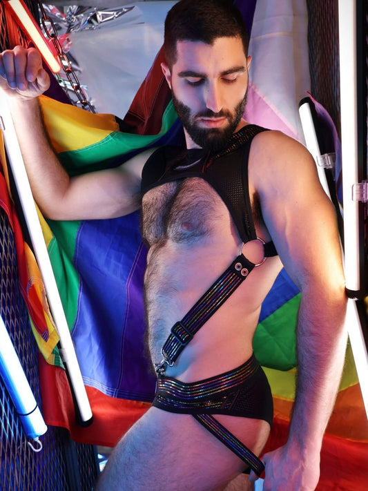 Man wearing a harness with a rainbow flag in the background