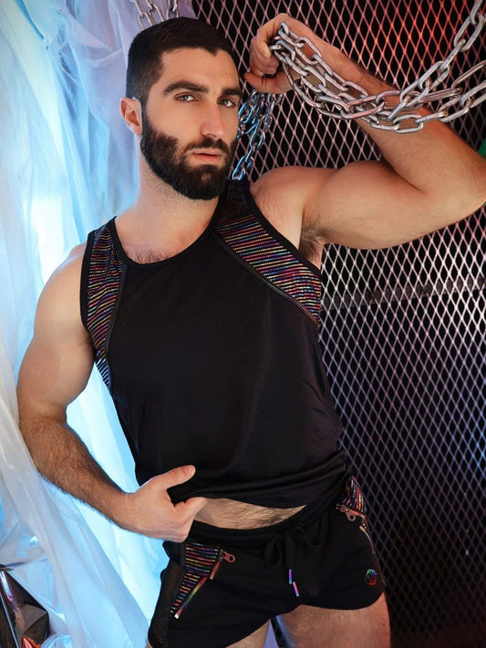 Man posing with chains, wearing a black tank top and shorts with colorful accents.