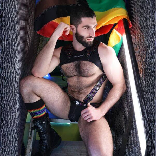 Man sitting on a chair with a rainbow flag in the background