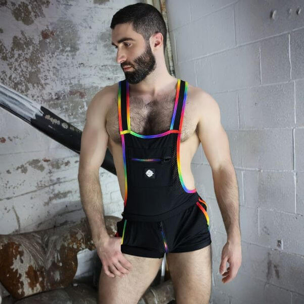 Man wearing a black unitard with rainbow straps in an industrial setting
