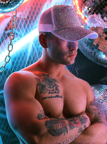 Man wearing a sparkly cap with tattoos in a disco setting