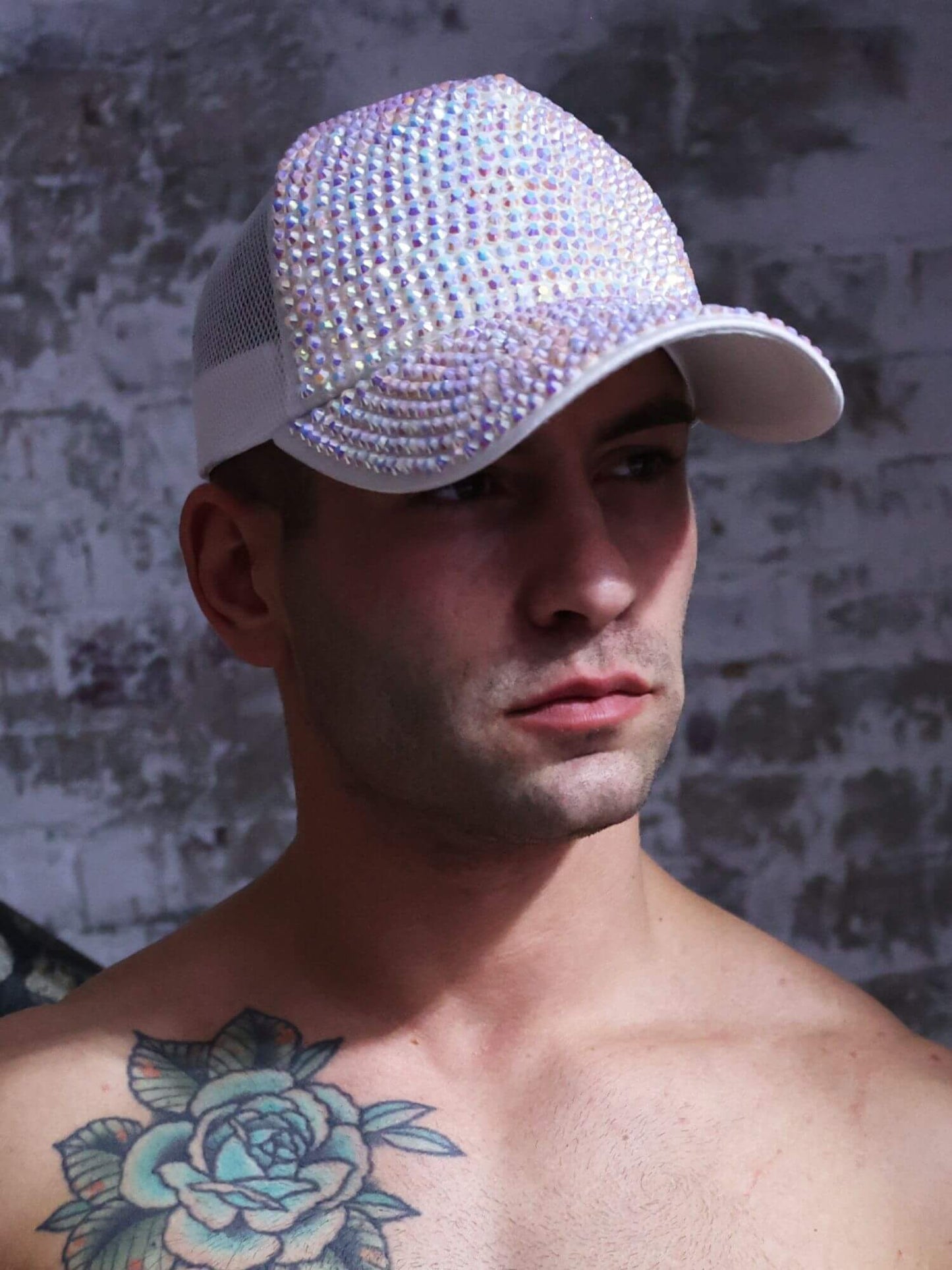 Man wearing a sparkly cap against a textured wall.