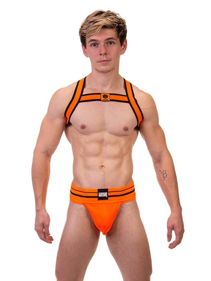 A male model wearing a neon orange and black elastic chest harness with the BARCODE Berlin brand emblem on the front horizontal strap.
