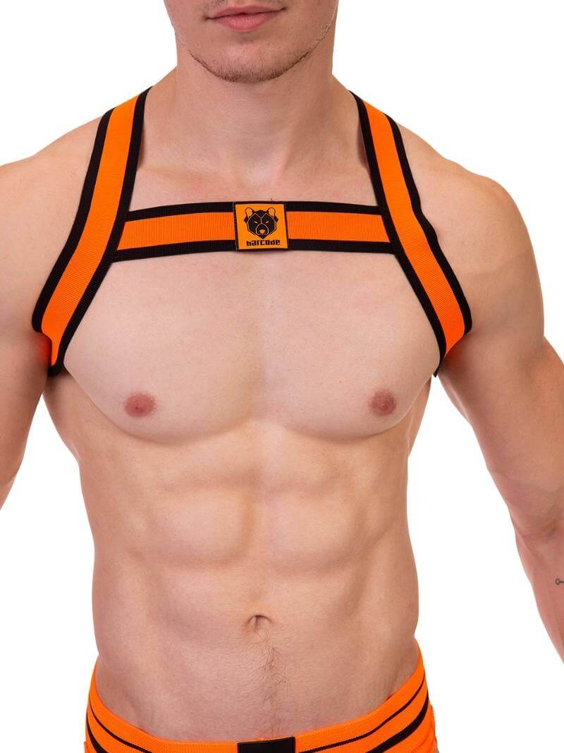 A male model wearing a neon orange and black elastic chest harness with the BARCODE Berlin brand emblem on the front horizontal strap.