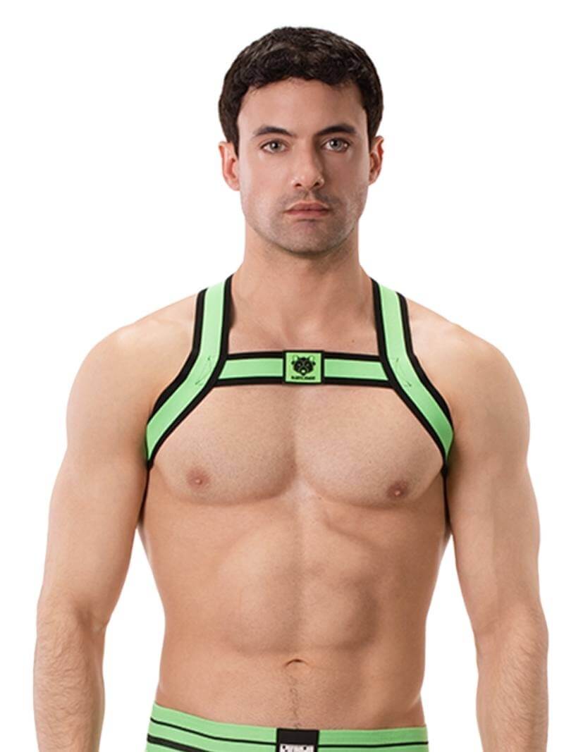 A model wearing a neon green and black elastic chest harness with the BARCODE Berlin brand emblem on the front horizontal strap.