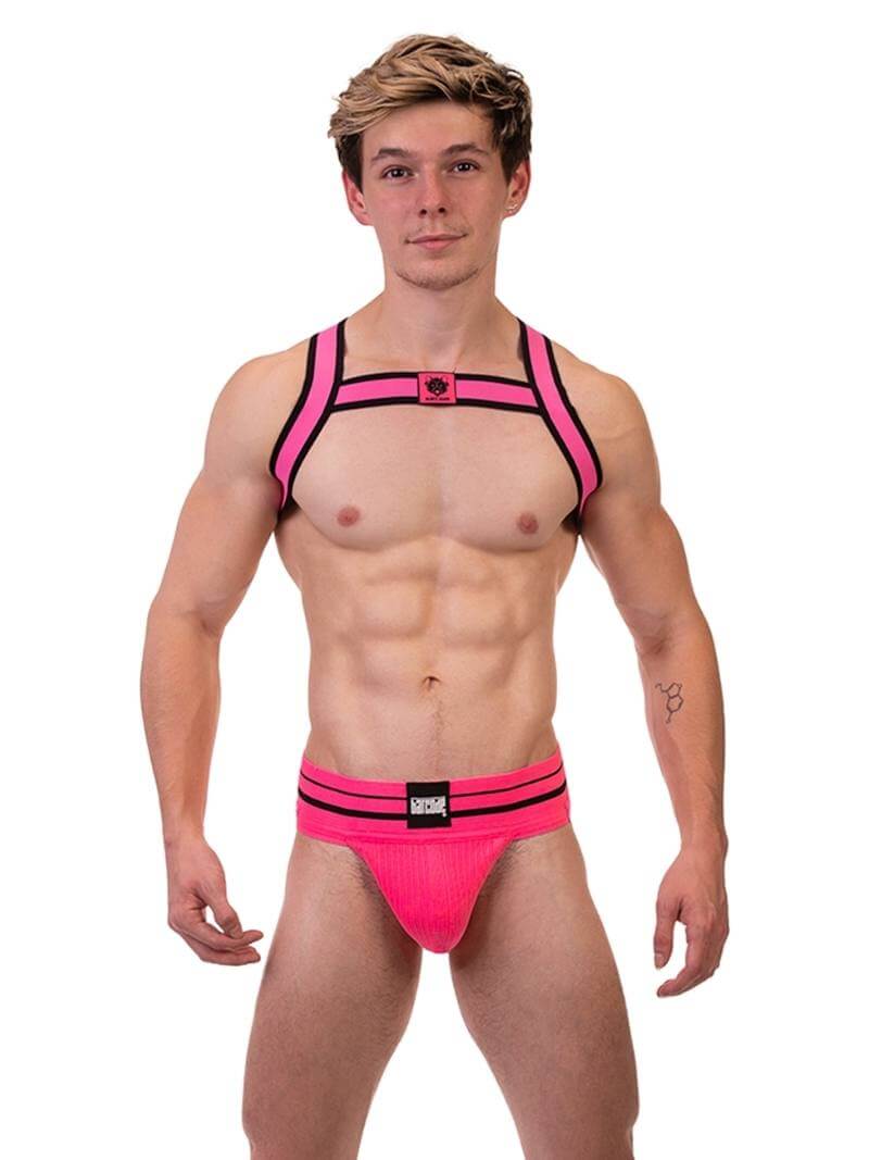 A model wearing a neon pink and black elastic chest harness with the BARCODE Berlin brand emblem on the front horizontal strap.