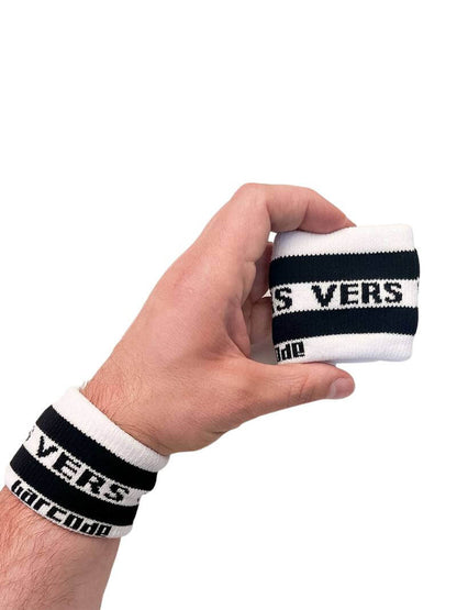 A hand holding two white wristbands with the text 'Top' written in black lettering and a black stripe design.