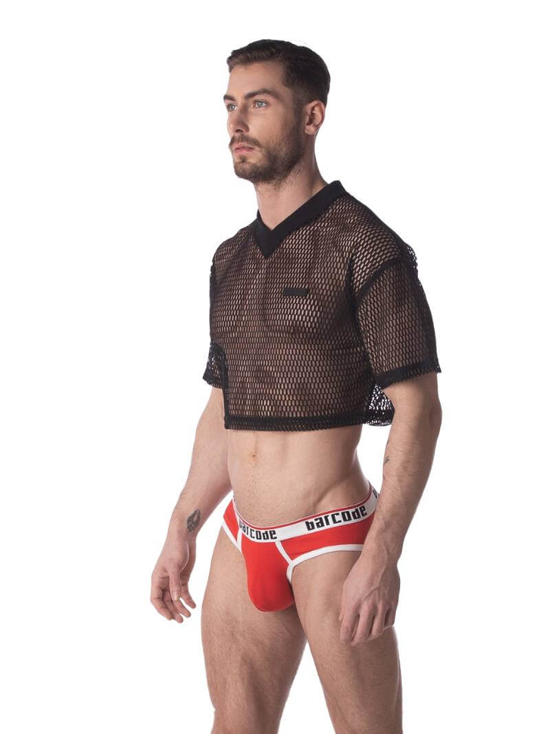 A male model wearing a black semi-see-through mesh fishnet crop top with short sleeves and a v-neck, branded with 'BARCODE'.
