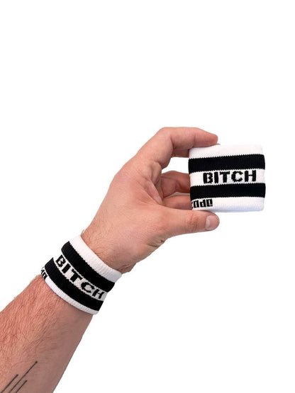 A hand holding two white wristbands with gay pride stripes