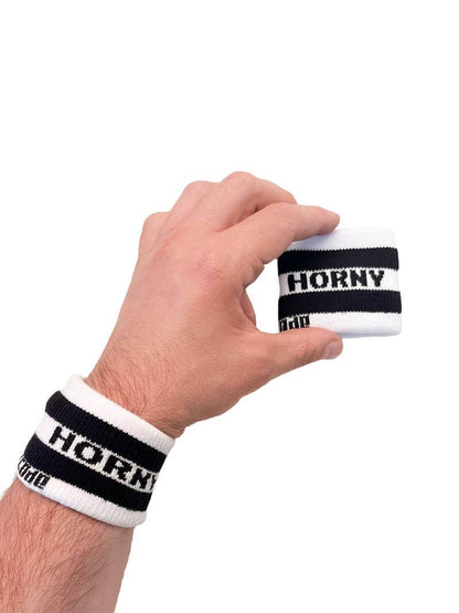 A hand holding two white wristbands with gay pride stripes