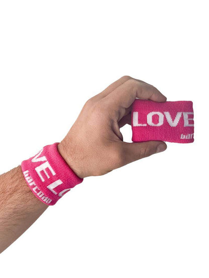 A hand holding two white wristbands with gay pride stripes