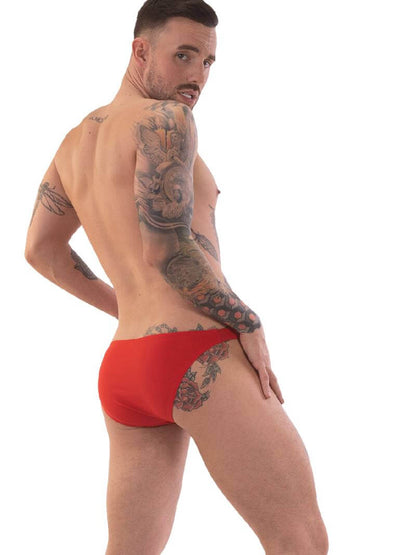 A person wearing red micro swimwear with a geometric pattern and the Barcode Berlin brand logo on the waistband.