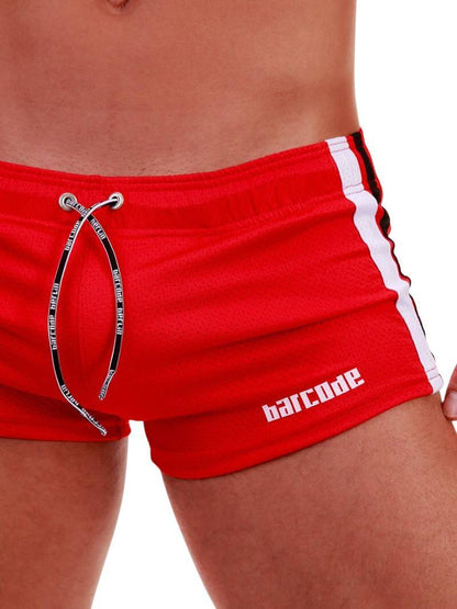 A model wearing black short-legged shorts with sporty side stripes and a drawstring waist.