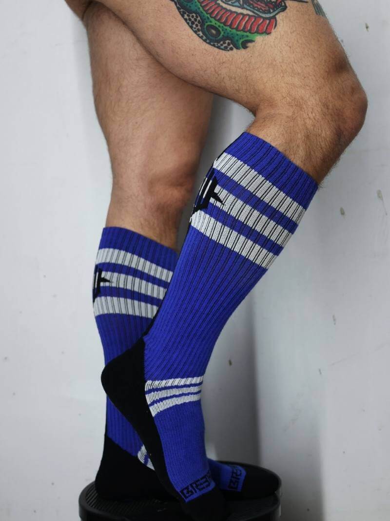 Blue knee-high socks with white stripes worn by a person on a plain background