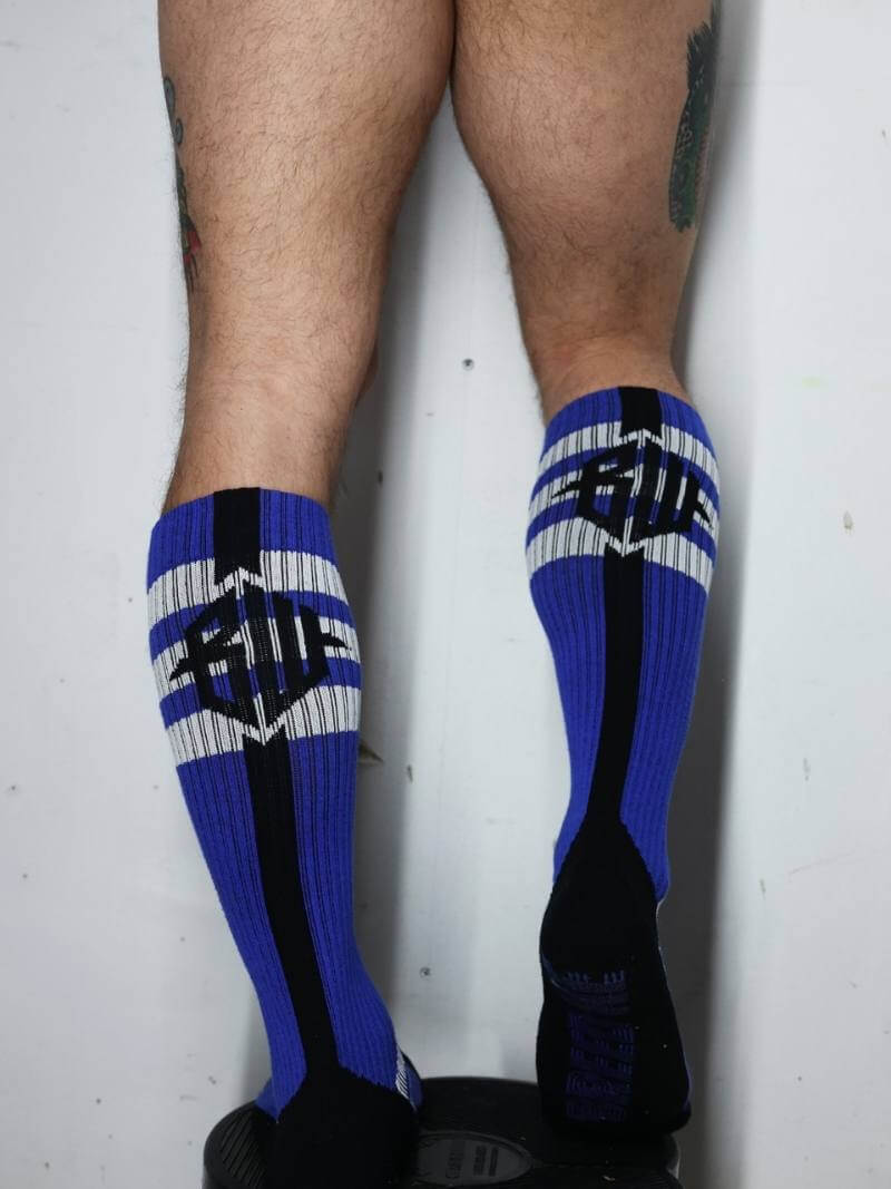 Blue and black knee-high socks with white accents worn by a person on a light gray background