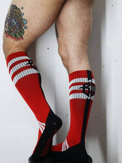 Red and black striped socks worn by a person with tattoos on a white background