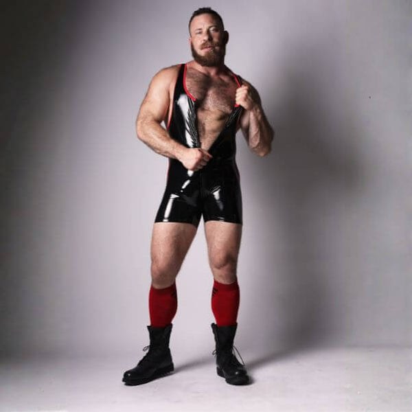 Man wearing a black wrestling singlet with red accents on a gray background