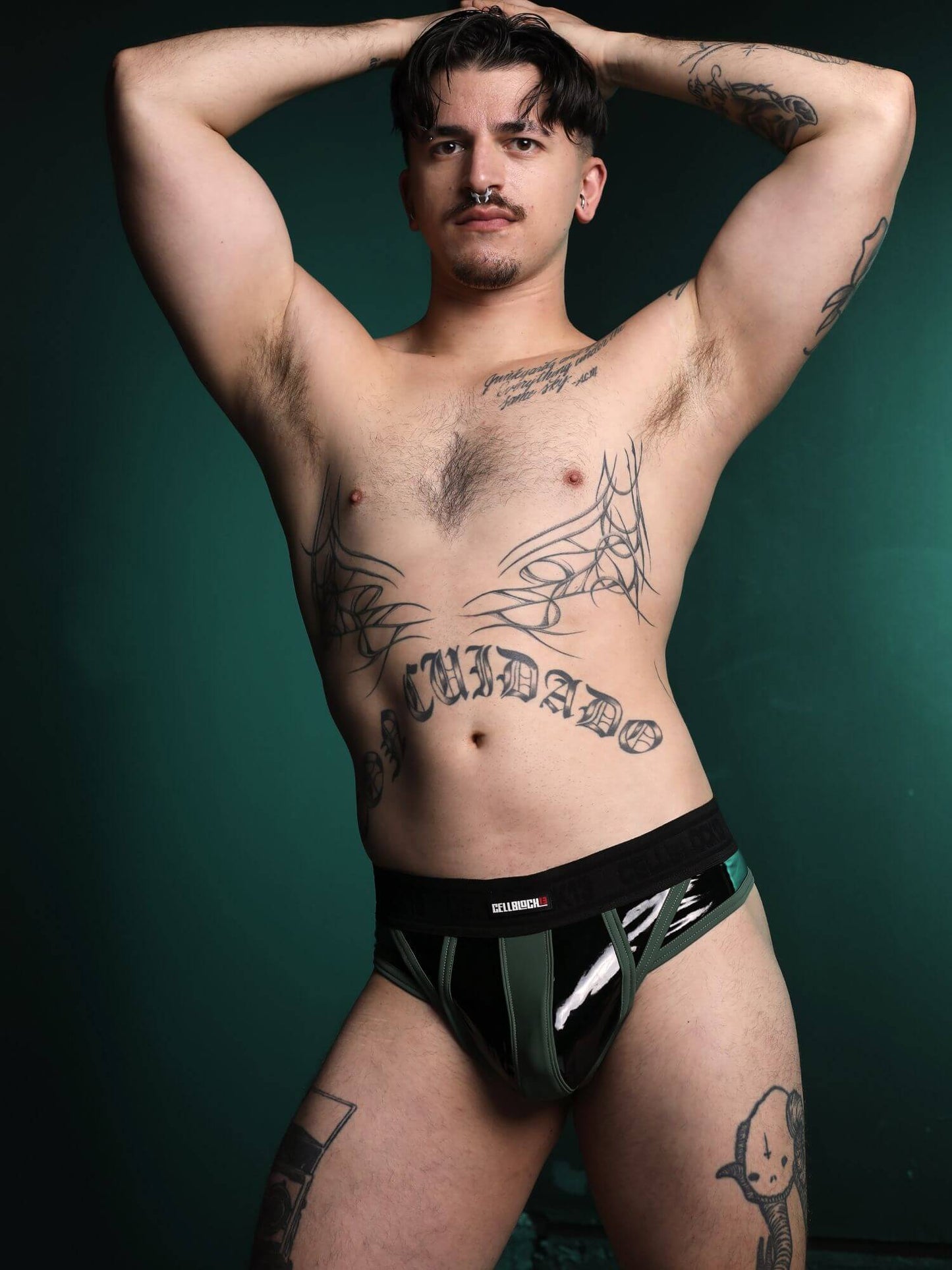Man wearing black underwear with visible tattoos on a dark background