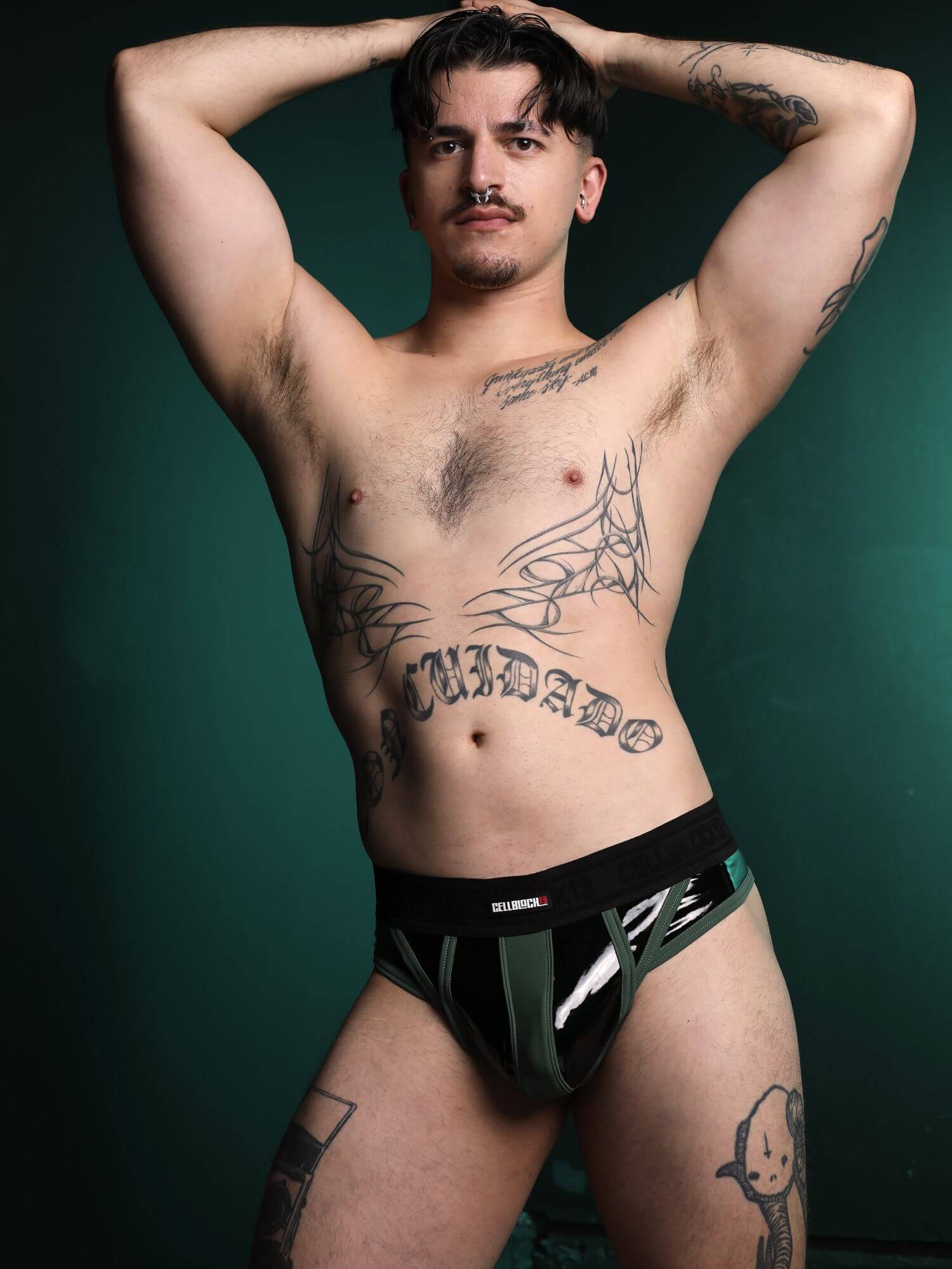 Man wearing black underwear with visible tattoos on a dark background