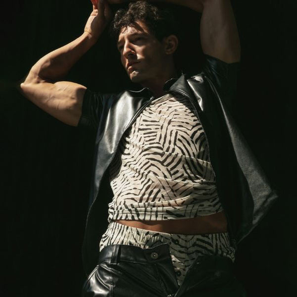 Person wearing a zebra print top and leather jacket against a dark background