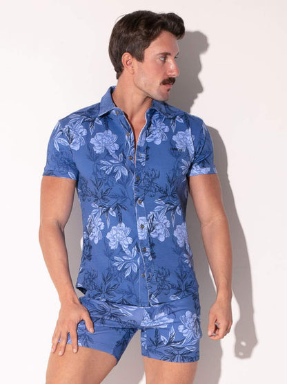 Man wearing a blue floral shirt and shorts on a white background