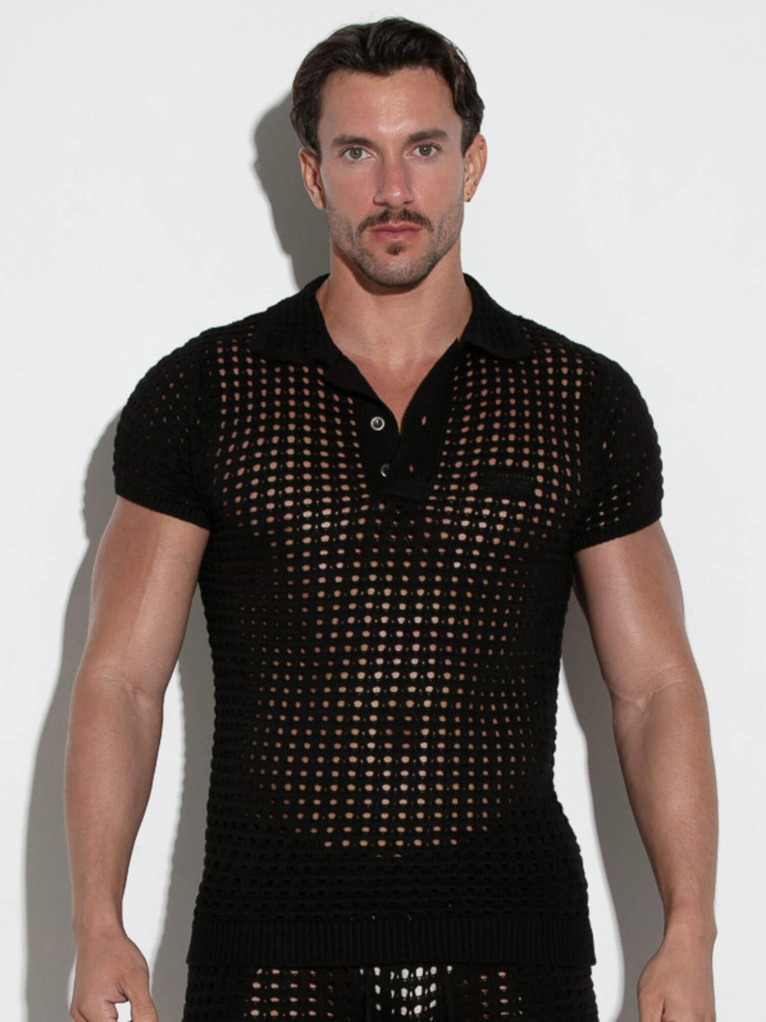 Man wearing a black mesh shirt against a white background