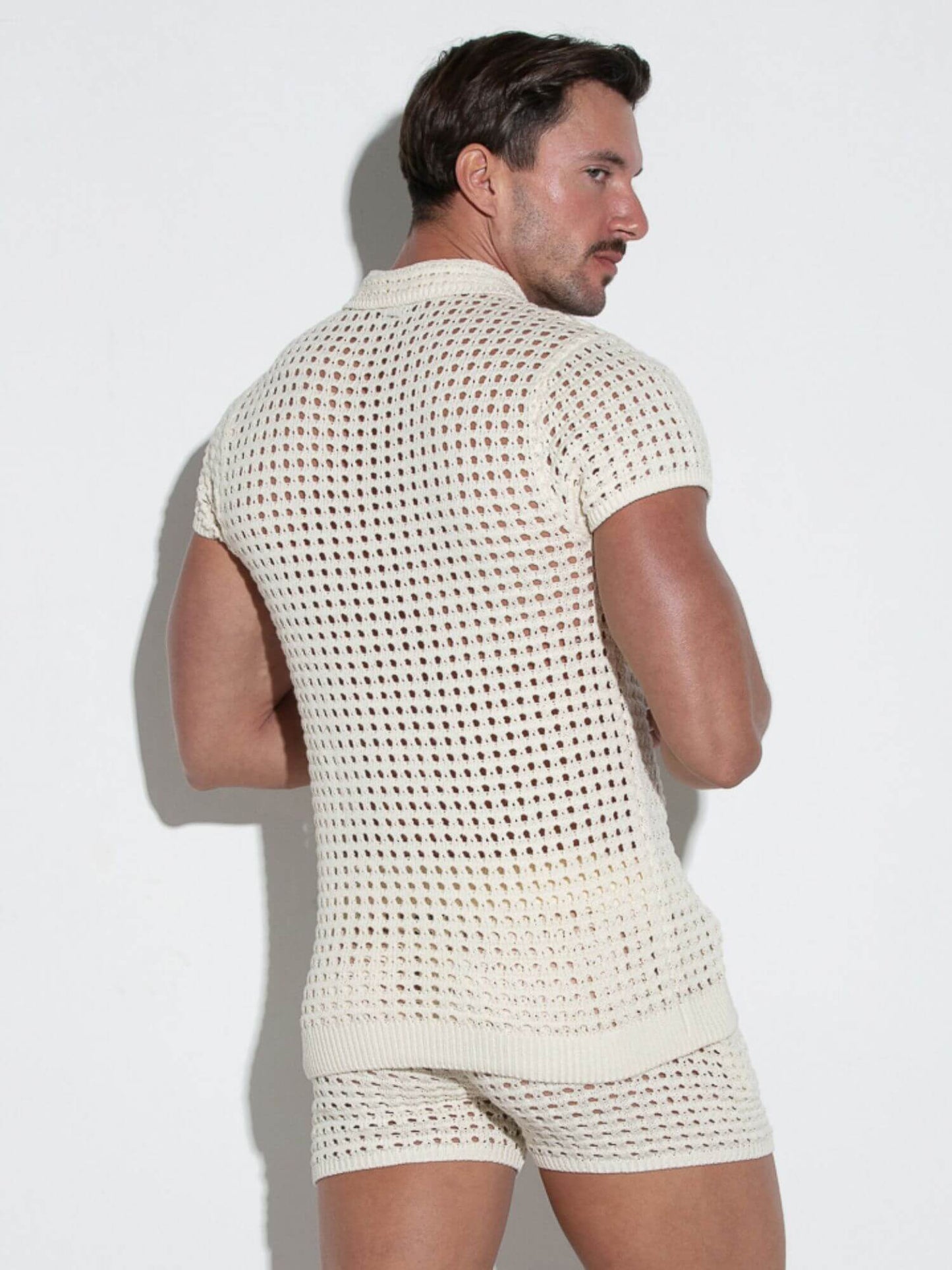 Man wearing a textured white sleeveless top and shorts against a light background