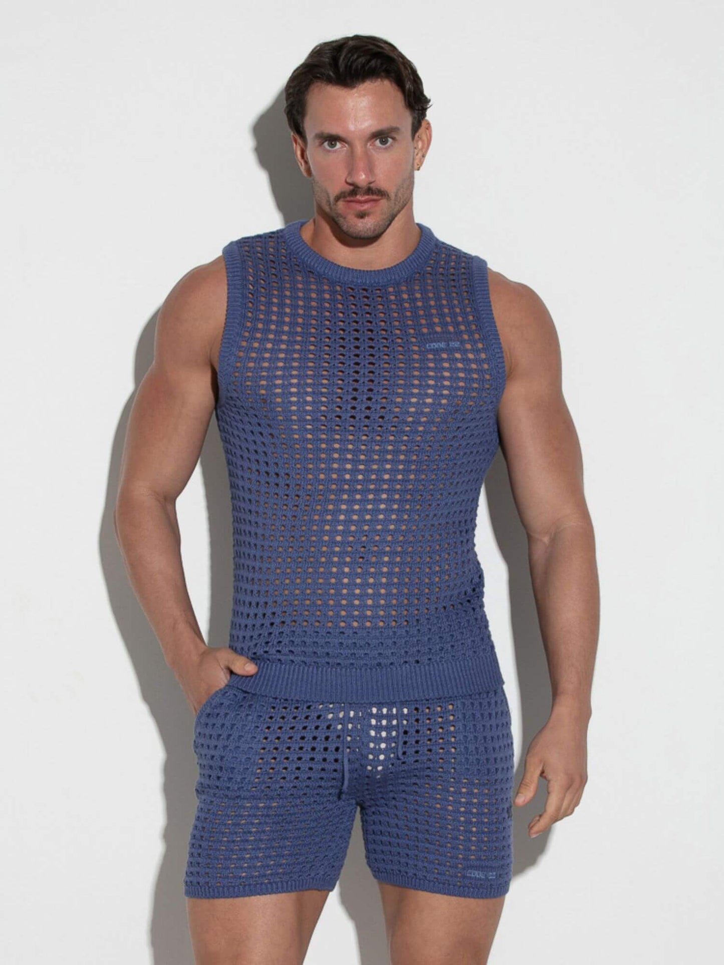 Man wearing a blue mesh sleeveless top and shorts against a white background