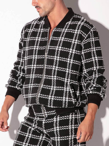 Person wearing a black and white checkered outfit against a gray background