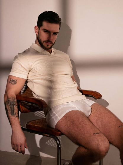 Man sitting on a chair wearing a light-colored shirt and white underwear.